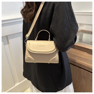 Detail view of the 'FASHION & BAG' embossed text on a beige minimalist crossbody bag