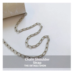 Detail shot of silver metal chain strap and beige jacquard fabric with letter pattern