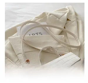 Detail of white crocodile embossed texture on a chic handbag with gold metal hardware