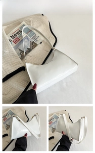 Detail view of a white crescent shoulder bag with glossy finish and gold metal zipper