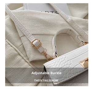 Close-up of white crocodile embossed leather bag with adjustable golden buckle