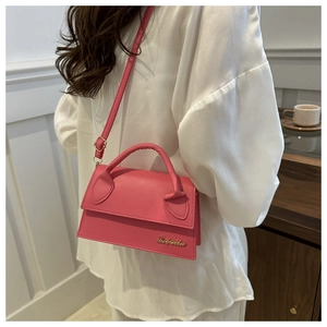 Detail of pink PU leather handbag with golden logo and matching shoulder strap