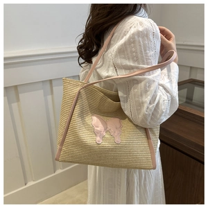 Detail of woven straw tote bag with pink bow accent on white lace dress