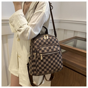 Detail of checkered plaid backpack with gold zipper hardware and brown adjustable straps