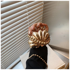 Detailed view of mirror gold shell evening bag with golden bead trim and glossy texture