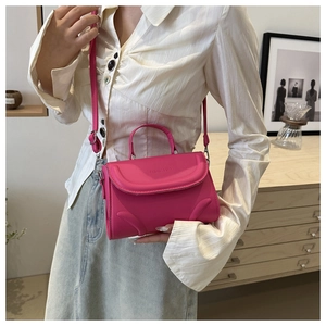Detailansicht einer fuchsiafarbenen Umhängetasche mit geprägtem Fashion & Bag-Schriftzug