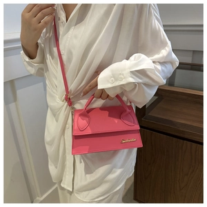 Detailed close-up of pink mini crossbody bag with gold metal logo on smooth leather