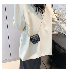 Detail view of mini checkerboard crossbody bag with gold chain on a beige blazer