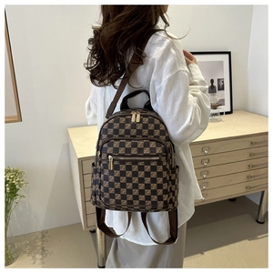 Detail of checkered mini backpack with golden zippers and adjustable brown straps