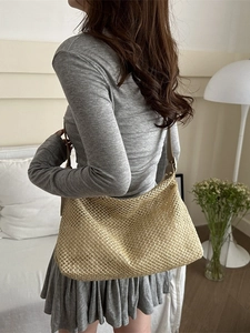 Sac fourre-tout en paille tissé main avec lanières en cuir porté par un modèle