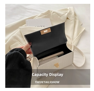 Detail showing white crocodile pattern bag interior capacity with phone and lipstick