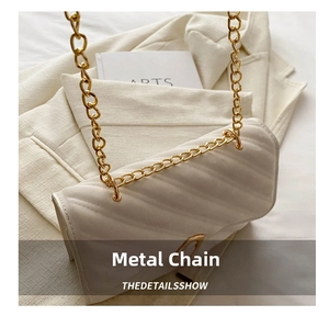 Close-up of off-white pleated shoulder bag with chunky gold chain strap and soft leather texture