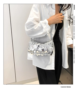 Close-up of silver sequin shoulder bag with metal chain strap on a female model