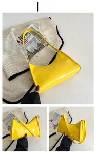 Detail of a glossy yellow crescent hobo bag with matching strap in a stylish setup