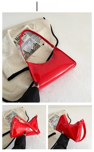 Detail of red glossy patent leather underarm bag with zipper closure and long strap