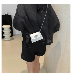 Detail of white textured leather mini crossbody bag with a silver spherical rotating lock