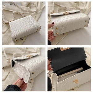 Detail view of white crocodile embossed bag with metal buckle and spacious interior
