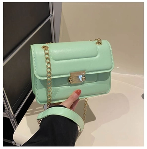 Detail of mint green quilted crossbody bag featuring a gold chain and metal buckle
