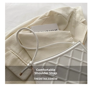 Détail d'un sac à main matelassé blanc avec bandoulière cylindrique et ferrures dorées