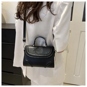 Detail view of black faux leather handbag showing silver buckle and debossed fashion logo