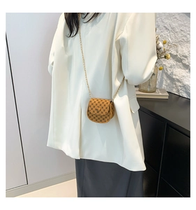 Detailed view of mini crossbody bag with vintage print and gold chain on model