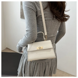 Detail of white crocodile pattern shoulder bag with golden metallic twist lock on strap