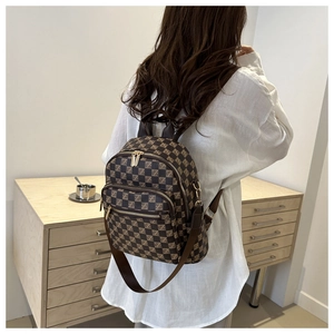 Detail of checkered casual backpack showing metal zipper and side D-ring on the shoulder strap