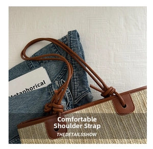 Detail of woven straw tote bag with brown leather shoulder strap and knot decoration