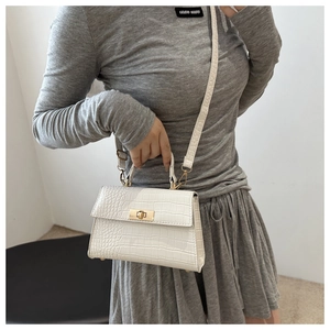 Detailed view of white crocodile pattern shoulder bag with golden turn-lock closure