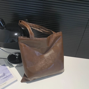 Borsa tote in pelle marrone con cuciture bianche mostrata su una scrivania essenziale