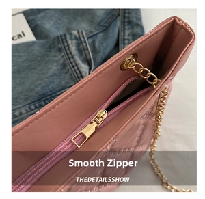 Close-up of golden smooth metal zipper and chain strap on pink quilted tote bag