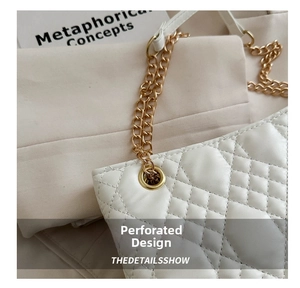 Macro detail of white quilted leather bag with gold chain strap and metal grommets
