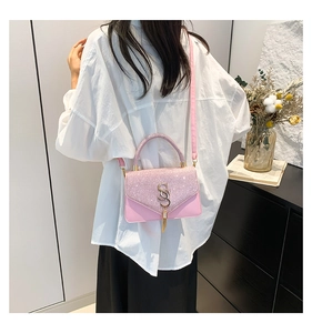 Rear view of a model wearing a pink shoulder bag with a gold S-logo and stylish tassel
