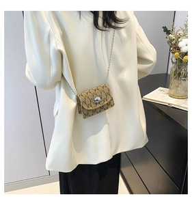 Detail of mini brown crossbody bag with M-pattern print and silver planet pearl buckle