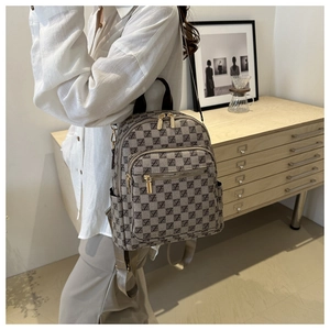 Detail of grey plaid backpack with gold zippers shown in a cozy home interior setting