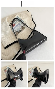 Detail view of glossy black patent leather hobo bag showing mirror finish and strap