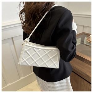 Détail du motif à losanges matelassés blancs sur un sac bandoulière avec nœud décoratif