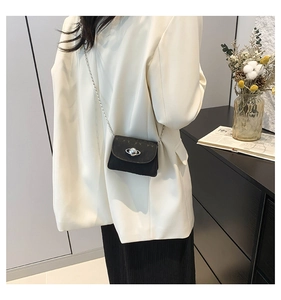 Detail of black mini crossbody bag featuring a silver planet logo and metal chain strap