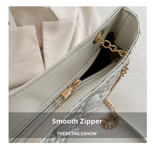 Close-up of smooth gold zipper hardware on white quilted faux leather tote bag