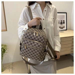 Close-up of khaki and brown patterned backpack with gold zipper and textured canvas fabric