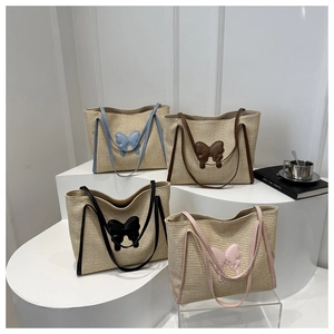 Detail view of woven straw tote bags with large bows in blue, brown, black and pink