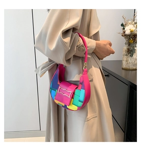 Detail of multi-color geometric block pattern and gold clasp on crescent shoulder bag