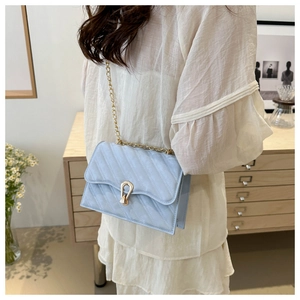 Detail of light blue quilted crossbody bag with gold chain and elegant metal clasp