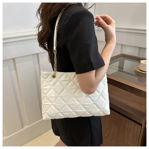 Close-up of quilted white leather tote bag with gold chain strap detail on model