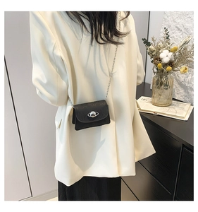 Detail of black mini crossbody bag with pearl planet clasp and embossed texture