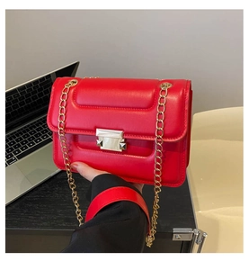 Detail of red quilted square bag with gold chain strap shown in an office setting