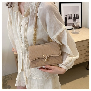 Detailed view of beige crossbody bag with quilted texture and gold chain strap