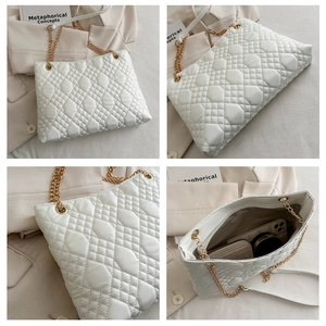 Detail view of large white quilted tote bag with golden chain strap and spacious interior