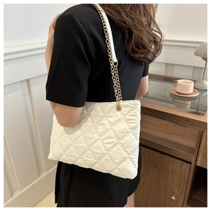 Detailed view of quilted tote bag with golden metal chain strap and white soft texture
