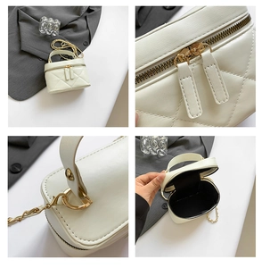 Detail of white quilted bucket bag with gold zippers and heart-shaped metal link chain